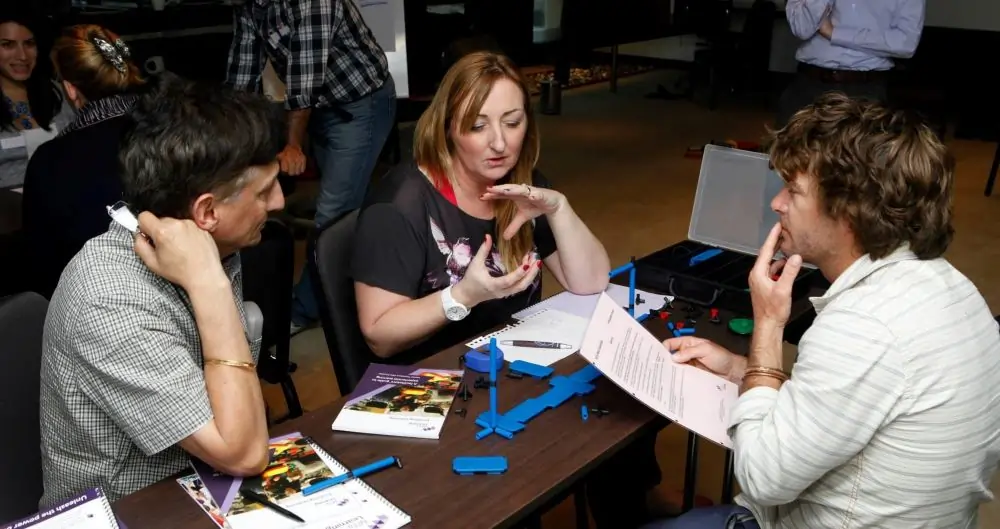 Participantes discutiendo el kit MTa Mini en una clase magistral, centrándose en la comunicación del equipo y la planificación de proyectos.
